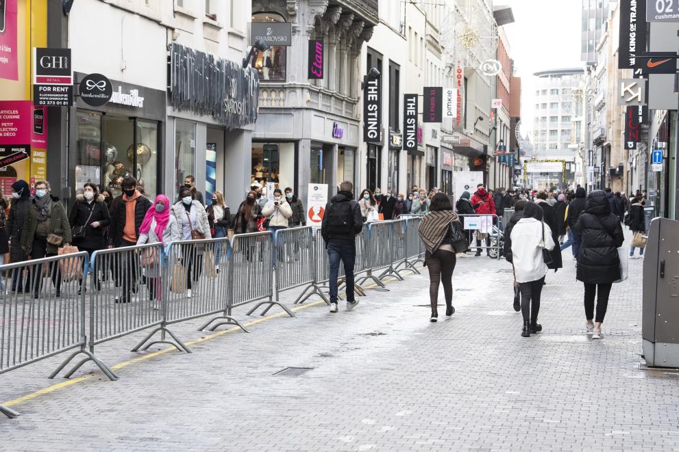 Busy shopping street in Brussels, divided by metal barriers, with two directions of flow of foot traffic