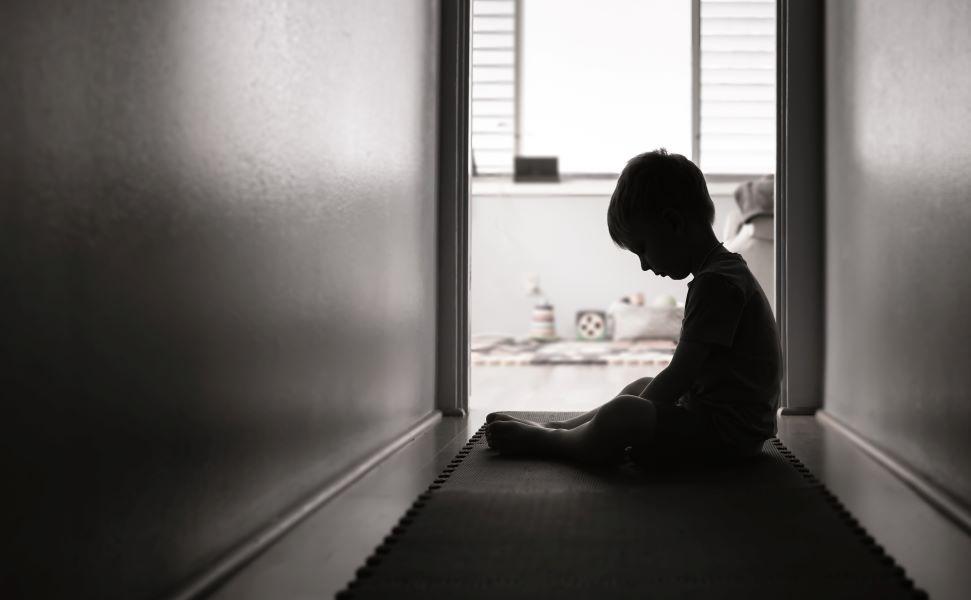 The image displays a sad child in a hallway