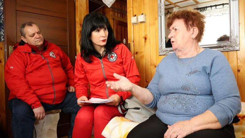 The image displays woman named Julia who accommodated 7 women from Ukraine. There are two employees of Slovak Red Cross (on the left) interviewing Julia.
