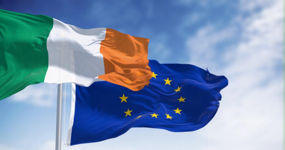 Against a clear blue sky, we see the flag of the Republic of Ireland and the flag of the EU.