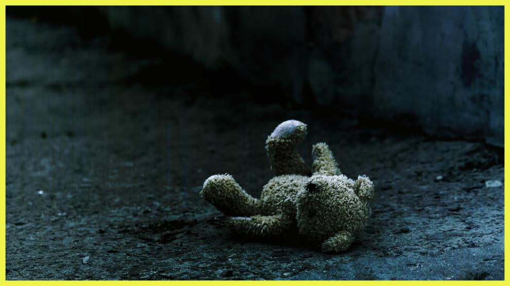 Against a gloomy background we see an abandoned teddy-bear, insinuating the absence of a child.  