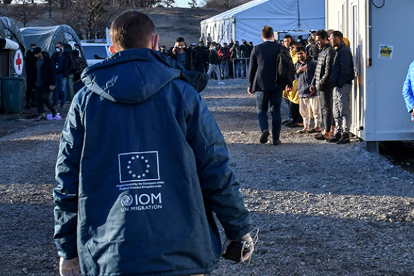 Image showing a First Reception Centre for refugees and migrants. At the centre we see a case worker, whose jacket displays the EU star symbol. 